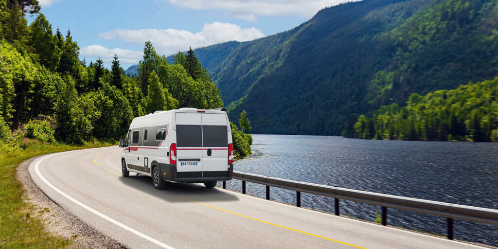 Fourgon Pilote roulant sur une route au bord d'un lac de montagne