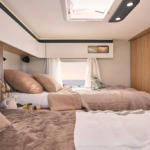 Chambre arrière d'un camping car profilé avec un lits jumeaux et des placards haut