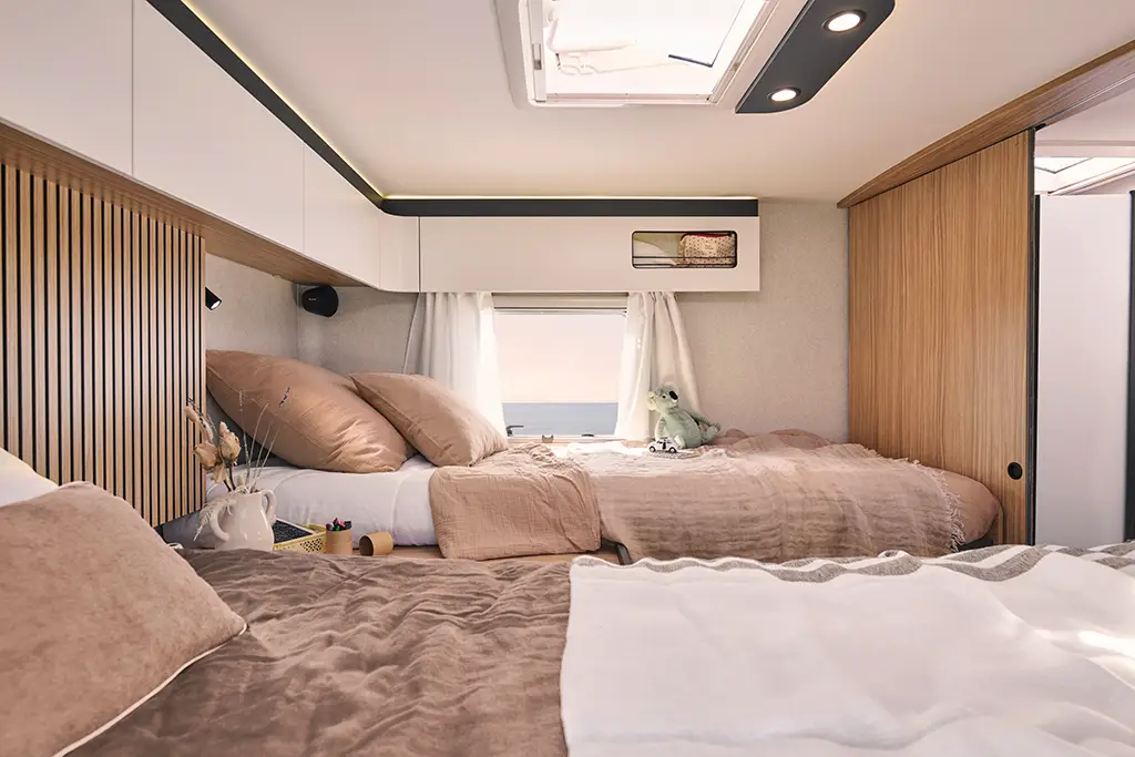 Chambre arrière d'un camping car profilé avec un lits jumeaux et des placards haut
