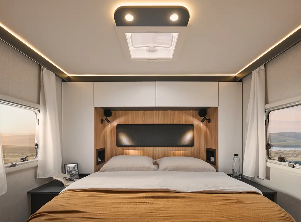 Chambre arrière d'un camping car profilé avec un grand lit et des placards